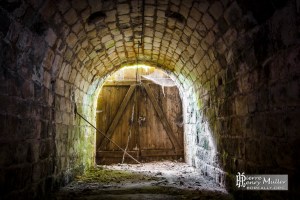 Sortie du tunnel fermée par une porte en bois laissant passer la lumière. Photo @CC Pierre-Henry Muller